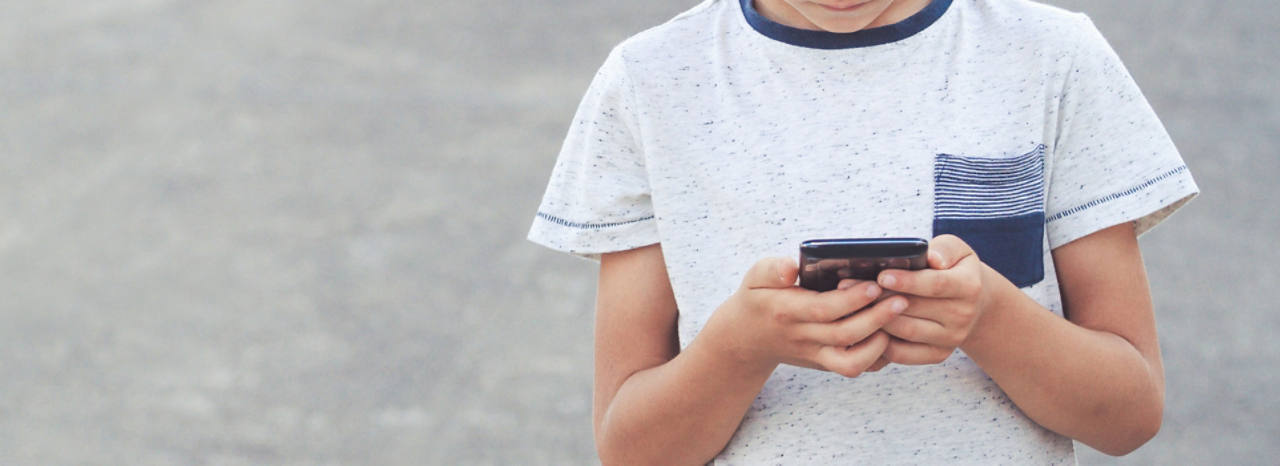 Kleiner Junge schaut auf sein Smartphone