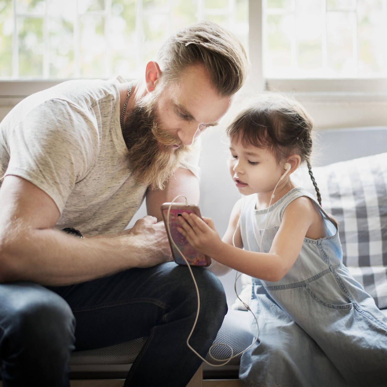 Vater schaut auf das Handy seiner kleinen Tochter