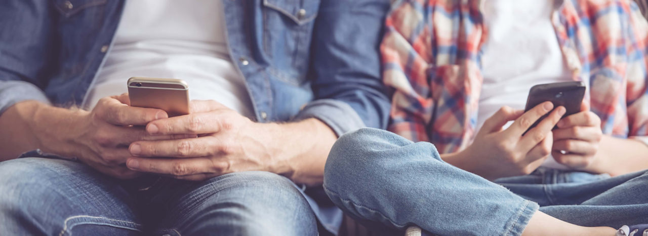 Vater und Sohn sitzen am Handy nebeneinander