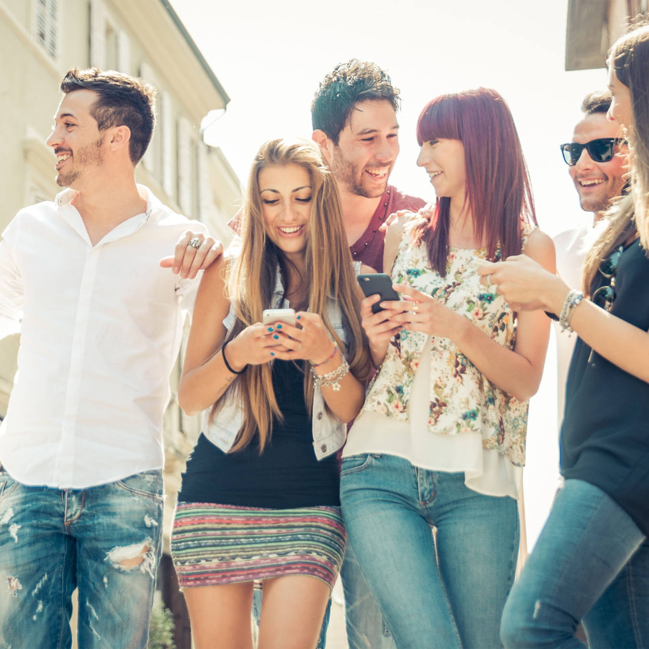 Lächelnde Studenten in der Gruppe mit Smartphones