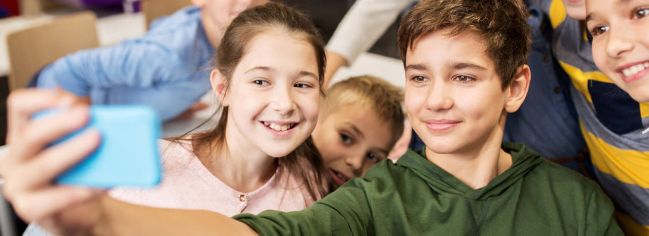 Vier Kinder machen ein Selfie mit ihrem blauen Smartphone