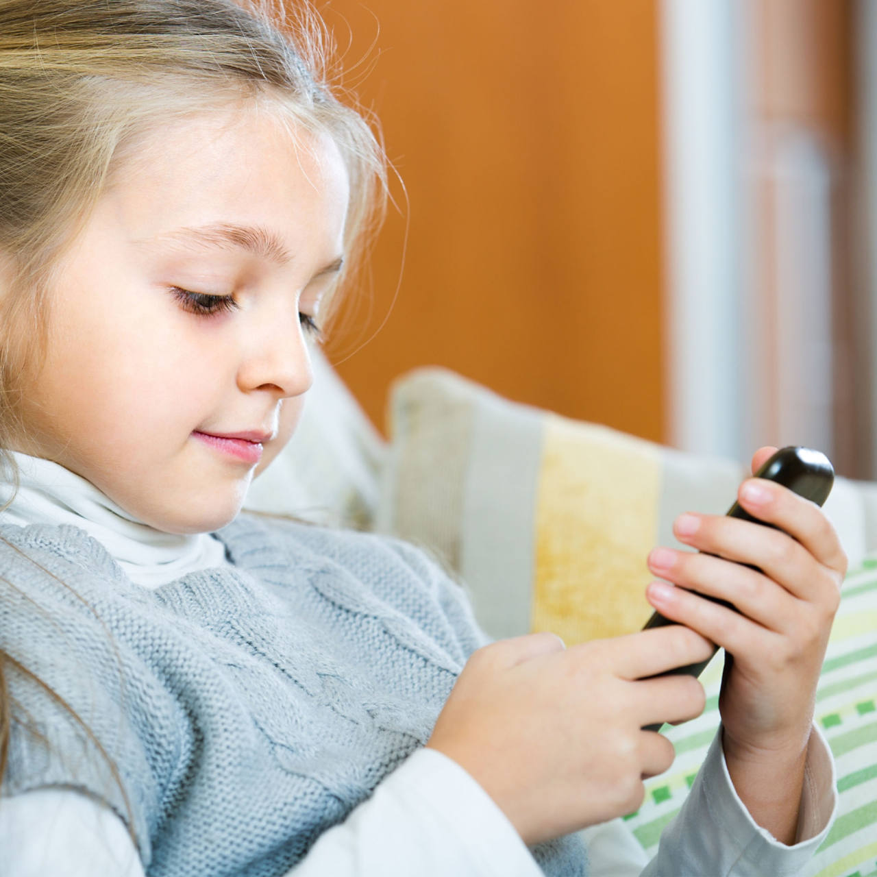  Junges Mädchen auf dem Sofa mit Handy in der Hand