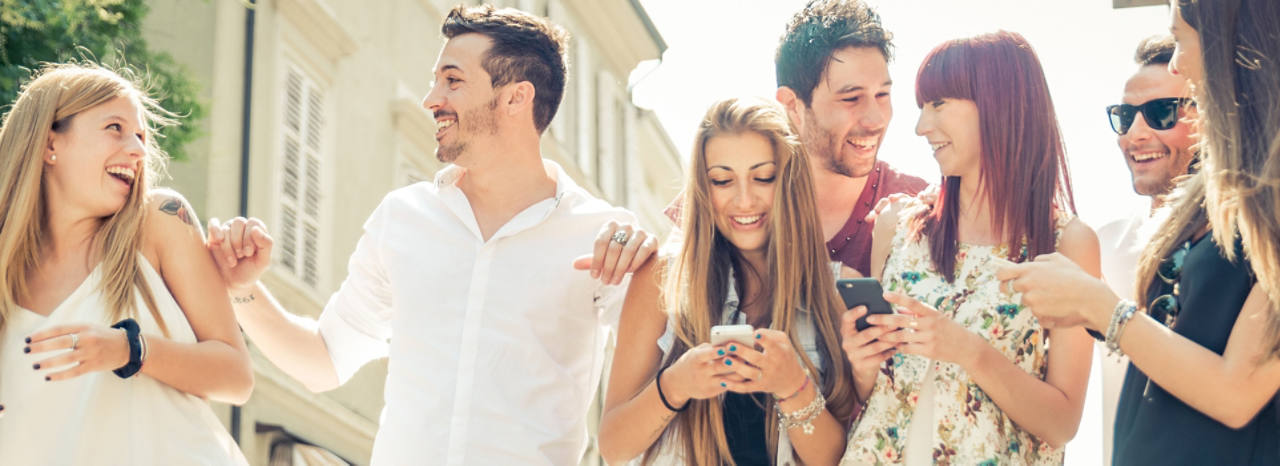 Gruppe von Studenten lachen gemeinsam mit ihrem Smartphone in der Hand